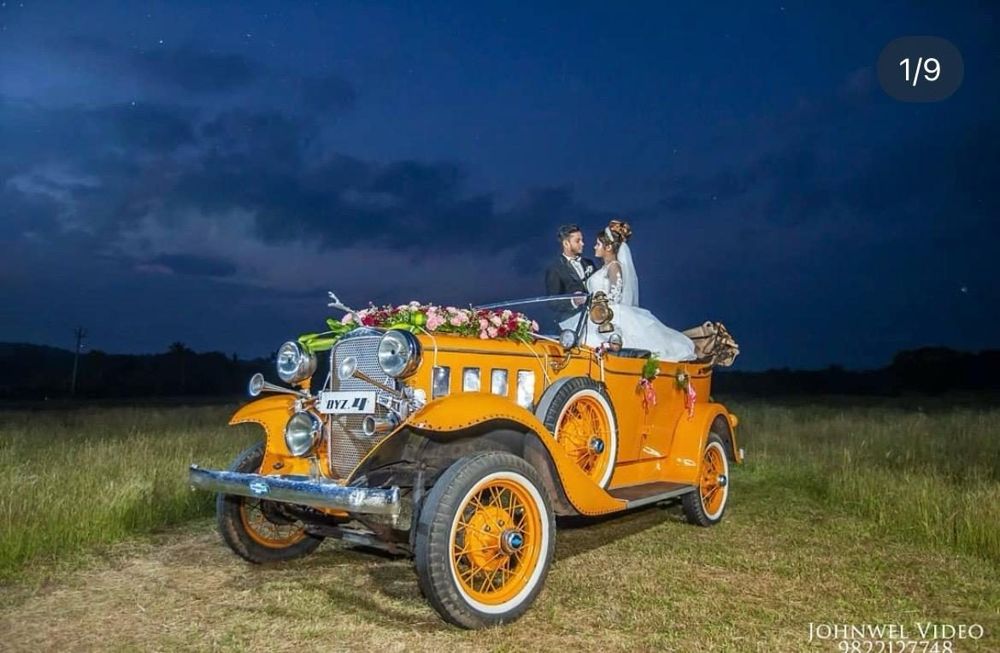 Couple in an orange vintage Chevrolet at dusk
