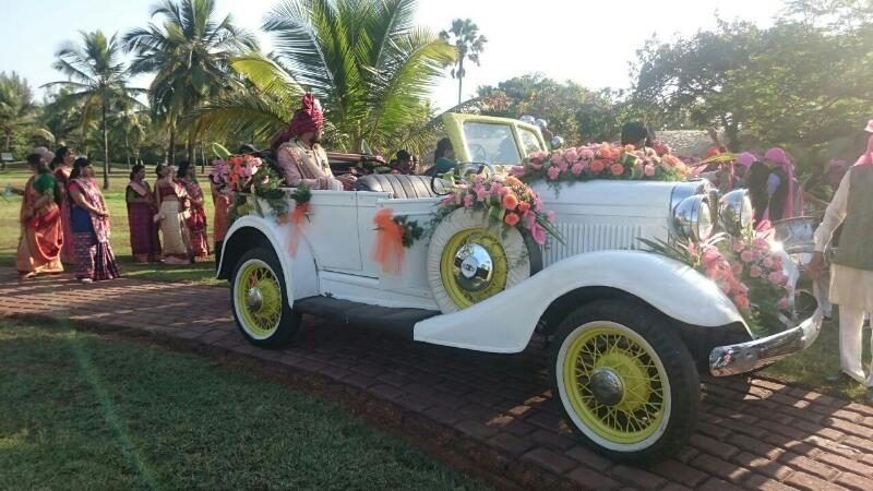 Grandfather's ivory vintage tourer with yellow wire wheels, decorated for a baraat