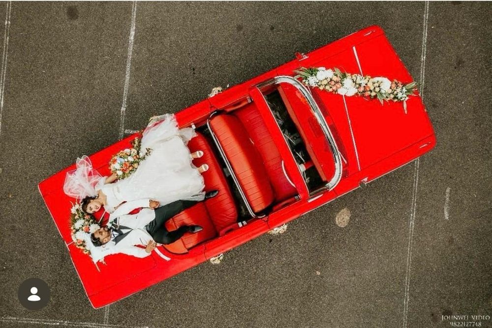 Aerial view of a couple lying on a red Impala