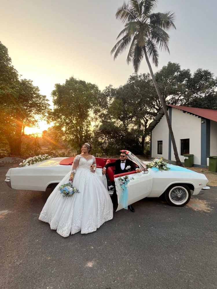 Bride and groom with the white convertible at sunset