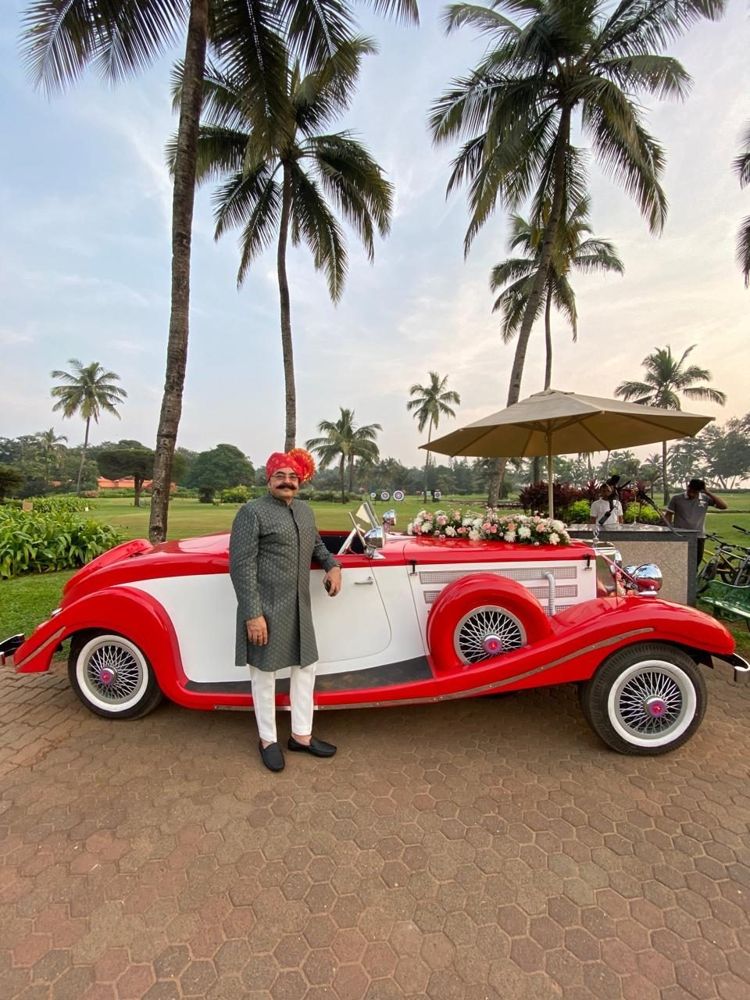 Guest in a turban beside the red and white roadster