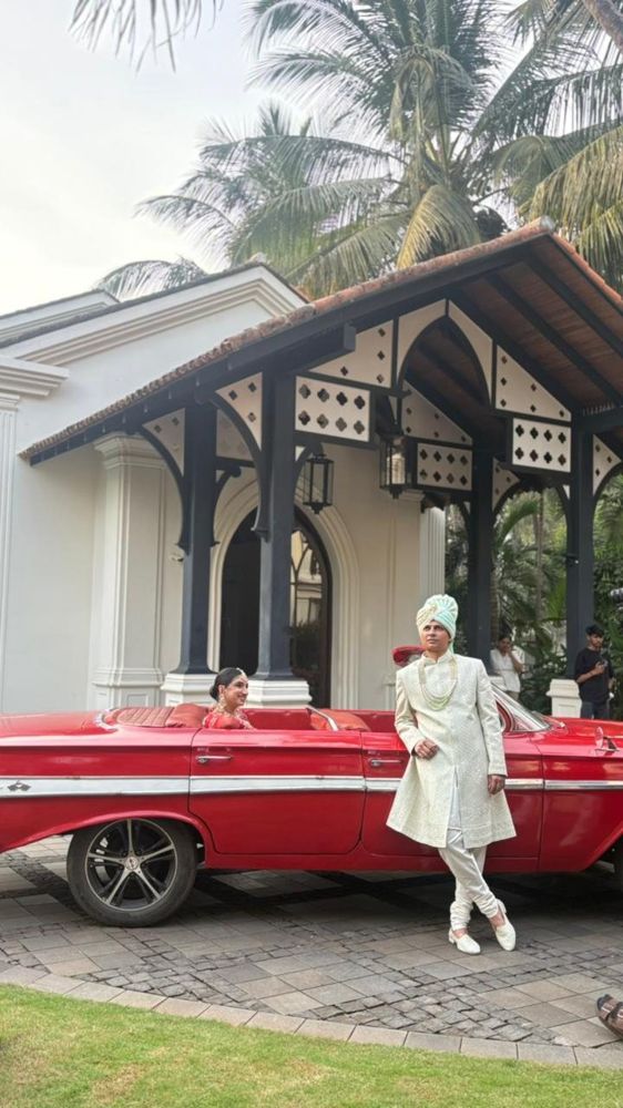 Groom in sherwani beside the red Impala