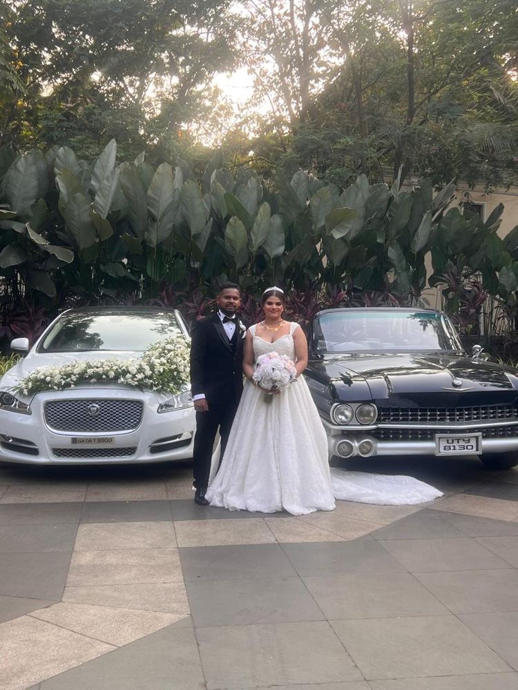 Couple between the Jaguar and the black Cadillac