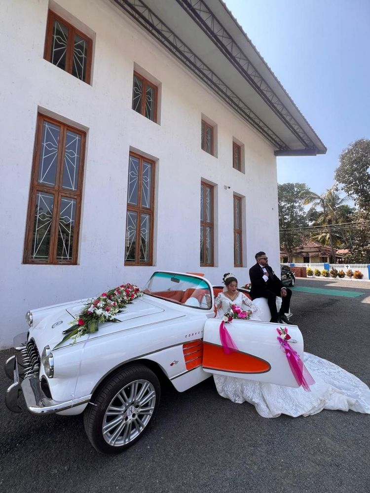 Bride and groom with the white Corvette outside a church