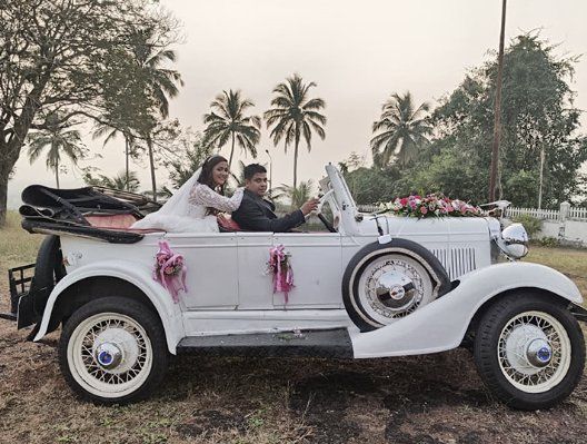 Bride and groom driving the white vintage tourer