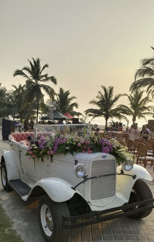 White Ford tourer decorated for a beach wedding at sunset